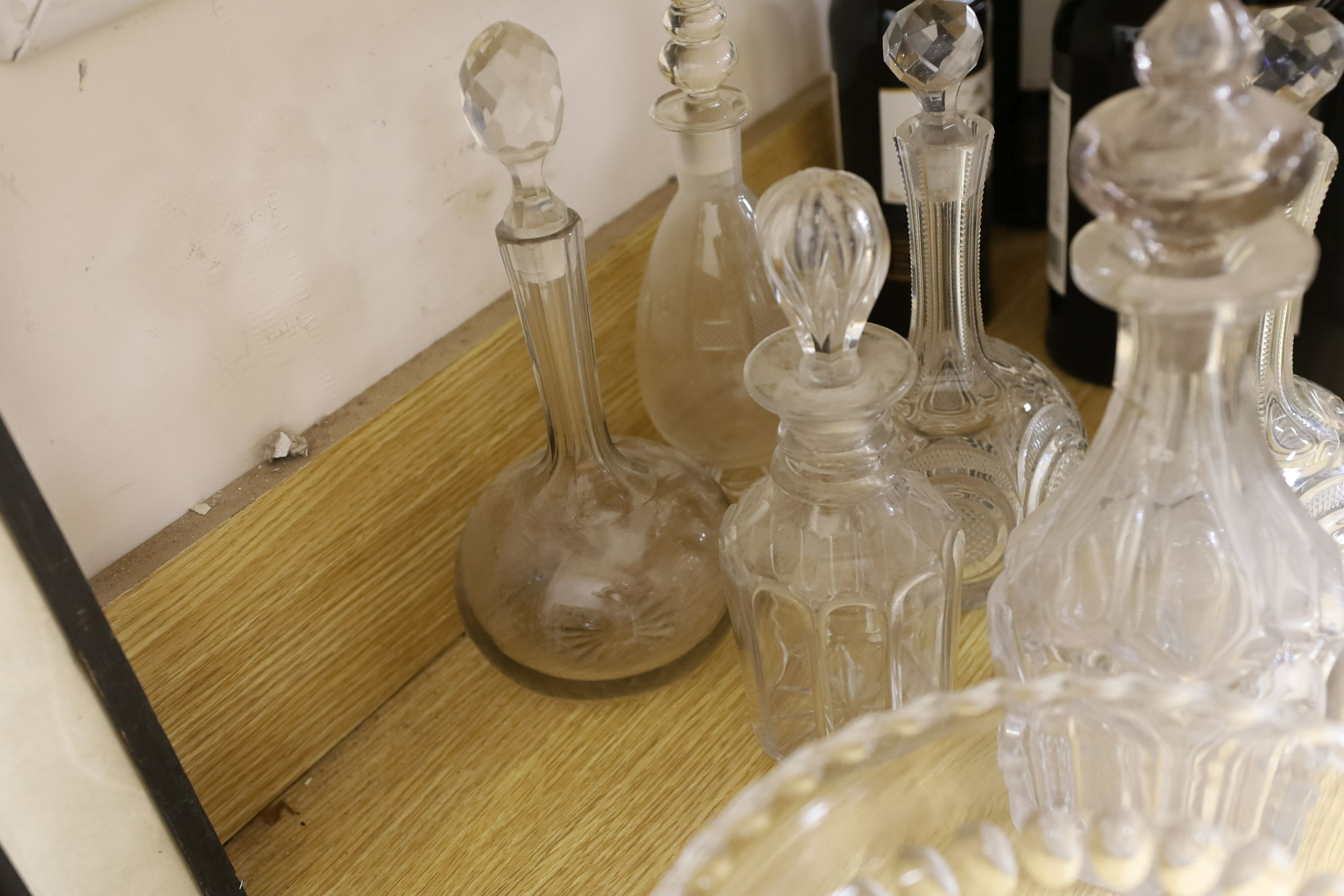 Sundry glassware including a six bottle cruet set on a plated stand, a Victorian cut glass jug, a pair of long neck decanters, five other decanters and a glass cake tazza